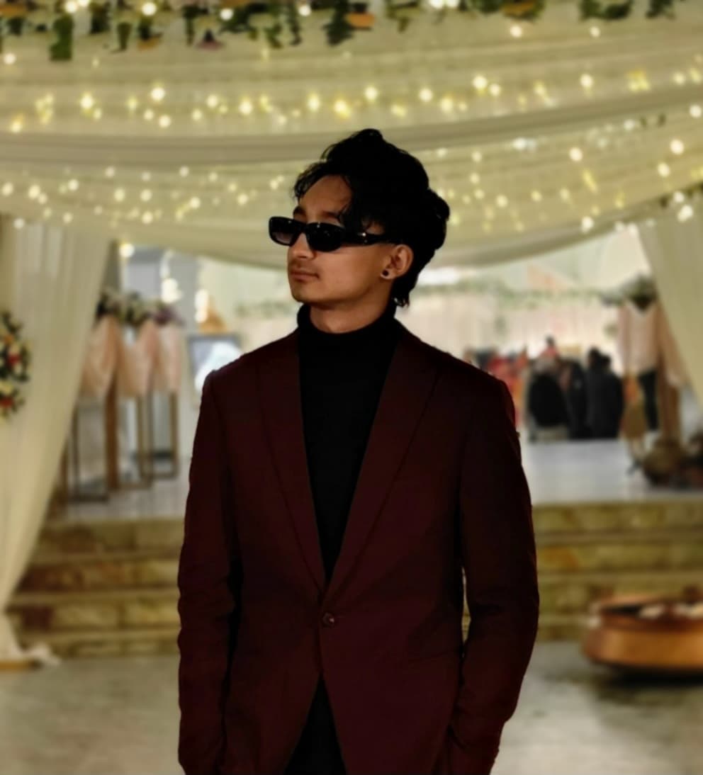 Portrait of Ashwin Shrestha in a dark red blazer and sunglasses at an evening event